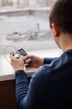 Parmak nabız oksimetresi kullanan bir adam, sağlık izleme konsepti. Beyaz arkaplanda nabız oksimetresi