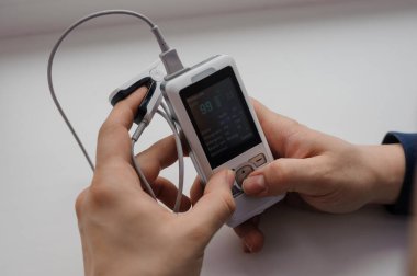 Parmak nabız oksimetresi kullanan bir adam, sağlık izleme konsepti. Beyaz arkaplanda nabız oksimetresi