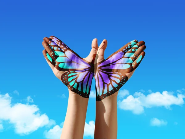Hand en vlinder hand schilderij, tattoo, over een blauwe hemel Rechtenvrije Stockfoto's