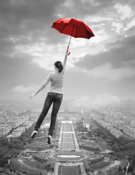 Young woman with red umbrella flying over Paris — Stock Photo, Image