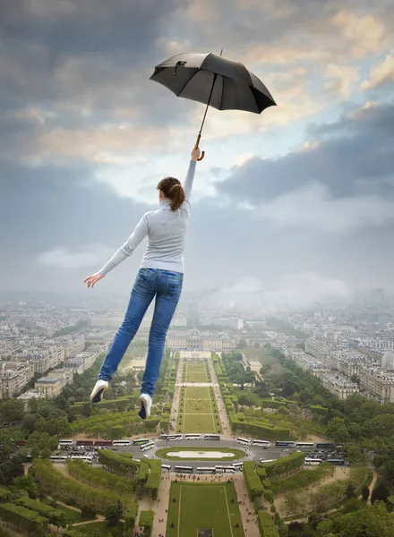 Mädchen mit Regenschirm fliegt über Paris. — Stockfoto