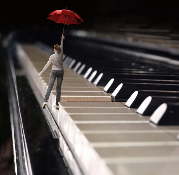 Женщина прыгает с зонтиком на клавиатуре пианино — стоковое фото