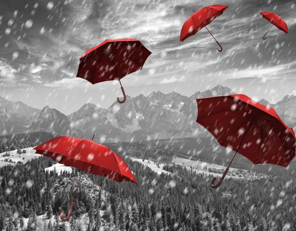 Flying red umbrellas in the mountains during a storm — Stock Photo, Image