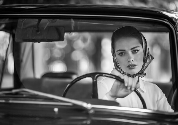 An attractive young woman girl looking at the camera from the front seat of the car
