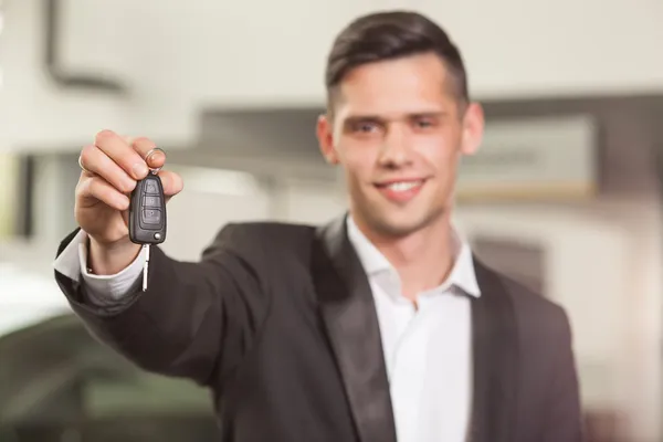 ¡Gran elección! Guapo joven vendedor de coches clásicos de pie en el concesionario con una llave — Foto de Stock