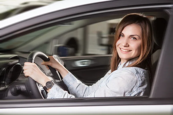 Join me for a drive. Attractive young woman sitting at the front seat of the car looking at camera — Stock Photo, Image