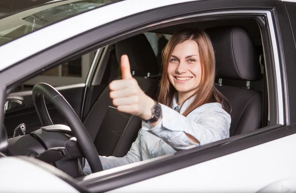 Join me for a drive. Attractive young woman sitting at the front seat of the car looking at camera — Stock Photo, Image