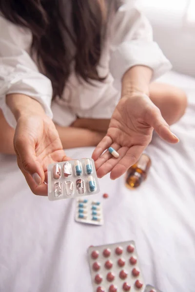 Yatakta depresif bir kadın, dağınık saçlı. Çok fazla ilaç alıyor ve anksiyete ve umutsuzluk içinde..