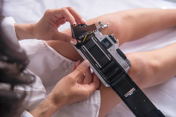 Genç bir kadın analog kameraya film rulosu yerleştiriyor.