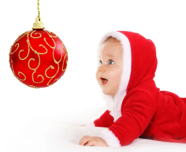 Weihnachtsbaby blickt auf eine rote Kugel — Stockfoto
