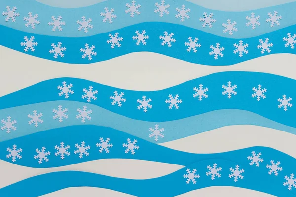 白い波状の紙シートと白い装飾的な雪の結晶とクリスマスの背景 — ストック写真