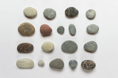 Beyaz zemin üzerinde çeşitli küçük yuvarlak taşlar koleksiyonu.