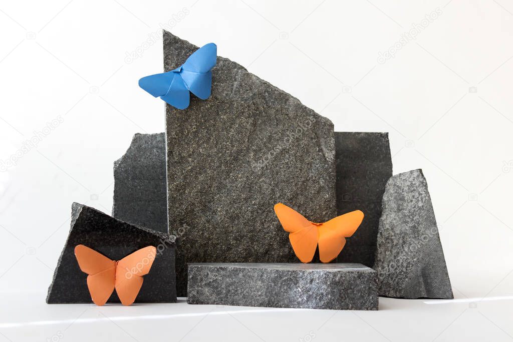 Abstract composition with stones and paper butterflies on white background.