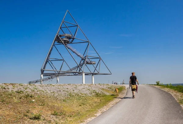 ドイツのボットロップにある四面体の丘の上に犬を歩いている男 — ストック写真