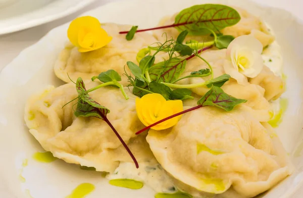 传统的煮熟的波兰肉饺子 用酸奶油和黄色花装饰 — 图库照片