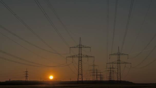 Timelapse linee elettriche al tramonto e turbina eolica — Video Stock