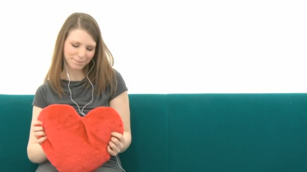 Ładna kobieta, słuchanie muzyki i pieszczoty z heart pillow — Wideo stockowe