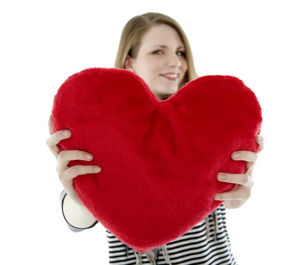 Woman smiling with heart shaped pillow — Stock Photo, Image