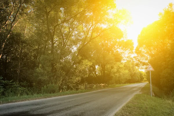 Ensam trafikerar vägen med strimma av solljus i solnedgången — Stockfoto