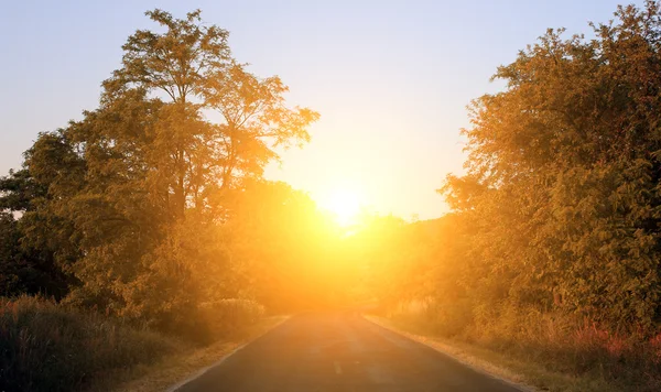 Carretera de tráfico solitario con rayo de luz solar al atardecer — Foto de Stock