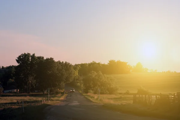 Asfaltweg met wolken en zonnestraal in zonsondergang — Stockfoto