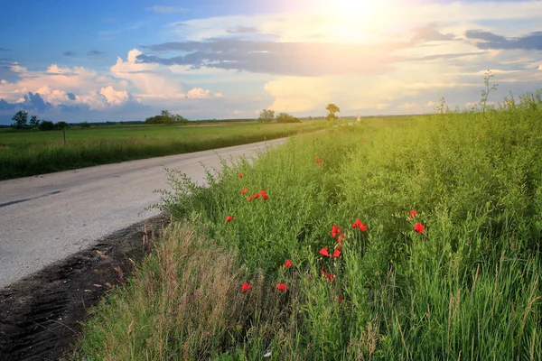 Asphalt road with clouds and ray of sunshine in sunset — Stock Photo, Image