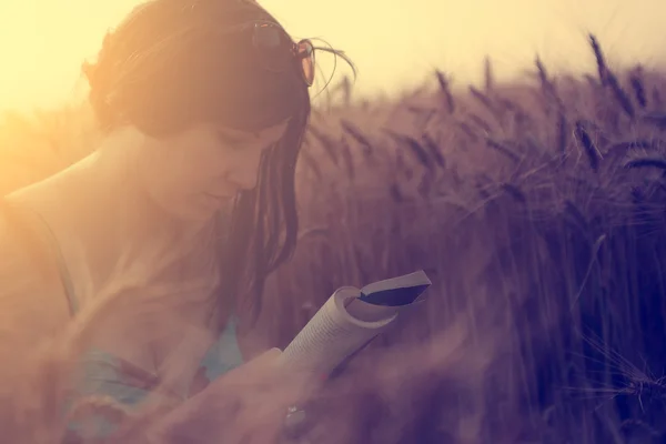 Bella donna che legge un libro in un campo di grano — Foto Stock