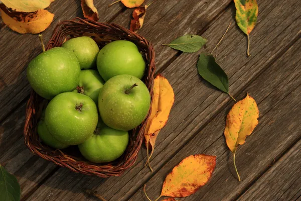 Apple on wooden table with fallen autumn leaves — Stock Photo, Image