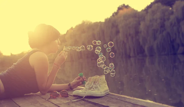 Beautiful woman blowing soap bubbles — Stock Photo, Image