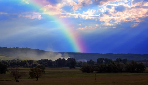 Rainbow over village after rain — Stock Photo, Image