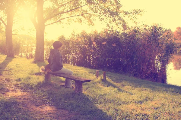 Vintage photo of woman sitting on bench with her dog — Stock Photo, Image