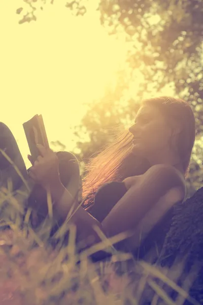 Foto einer jungen Frau, die im Park ein Buch liest — Stockfoto