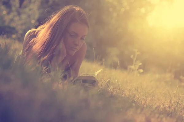 Foto einer jungen Frau, die im Park ein Buch liest — Stockfoto