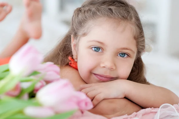 ピンクのチューリップと横になっている小さな女の子 ロイヤリティフリーのストック画像