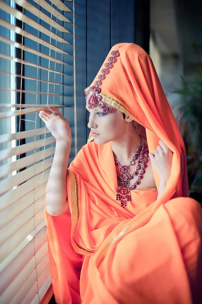 Girl in east clothes gazing out the window — Stock Photo, Image