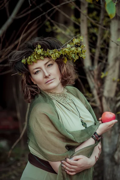 Mujer en corona de abedul sosteniendo manzana — Foto de Stock