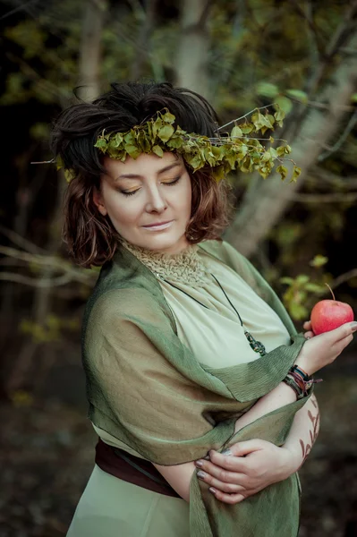 Kvinna i Björk krans holding apple — Stockfoto