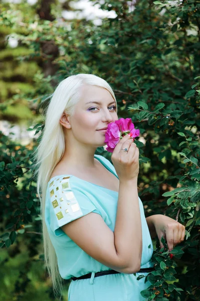 Blondin att lukta en blomma — Stockfoto