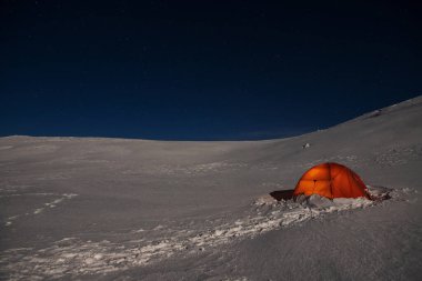 Yıldızlı gökyüzünün arka planındaki kış dağlarında çadır.