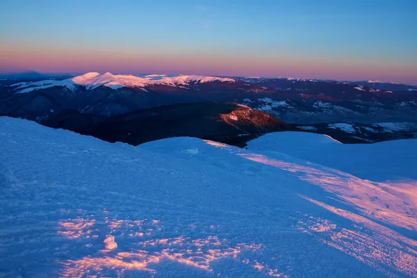 太陽が昇ると雪に覆われた山の頂が照らされ — ストック写真