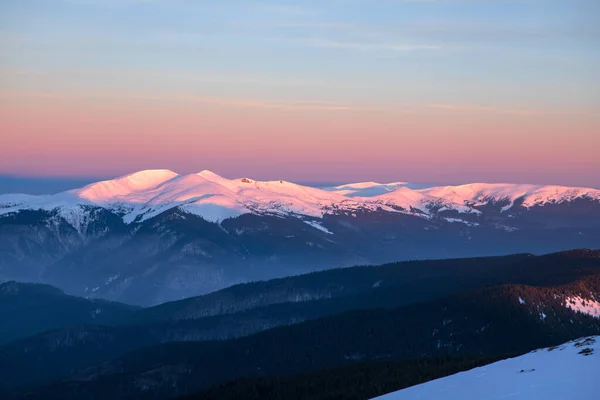 太陽が昇ると雪に覆われた山の頂が照らされ — ストック写真
