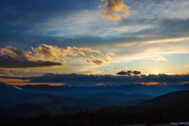 Dağlarda akşam gökyüzü, batan güneşle aydınlanıyor.
