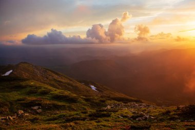 Akşam güneşiyle aydınlanan sis, dağların yamaçlarını kaplıyor. Karpatlar, Ukrayna.