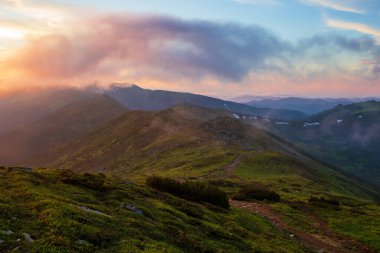 Akşam güneşiyle aydınlanan sis, dağların yamaçlarını kaplıyor. Karpatlar, Ukrayna.