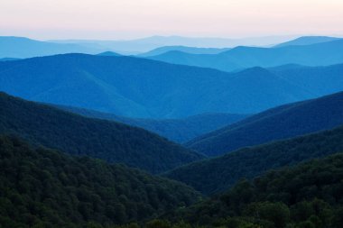Batan güneşin aydınlattığı dağ yamaçlarının muhteşem manzarası. Doğu Karpatlar, Ukrayna.
