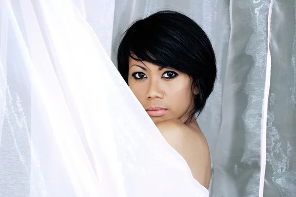 Girl standing at the door and wrapped in white tulle — Stock Photo, Image