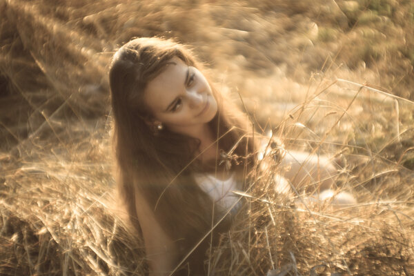Beautiful girl with long hair rests on the hay