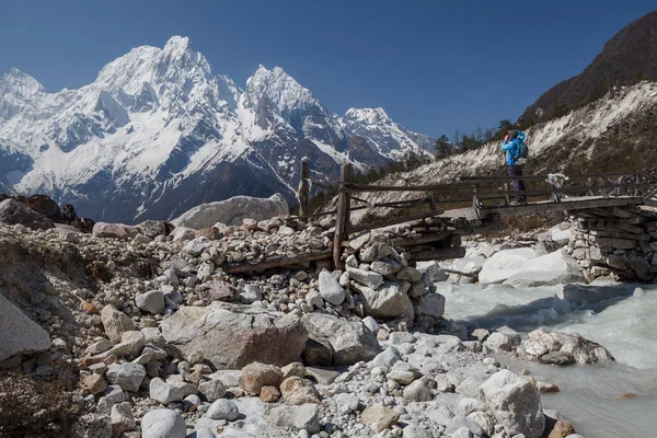 站在桥上的一位游客给白雪覆盖的群山拍照 喜马拉雅山 Bimtang — 图库照片