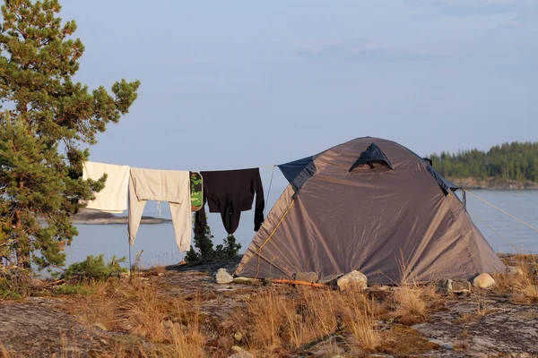 Tält och kläder på repet nära sjön — Stockfoto