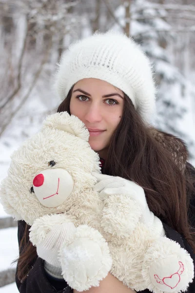 Cheerful Caucasian Young Woman in Snowy Weather holds a toy